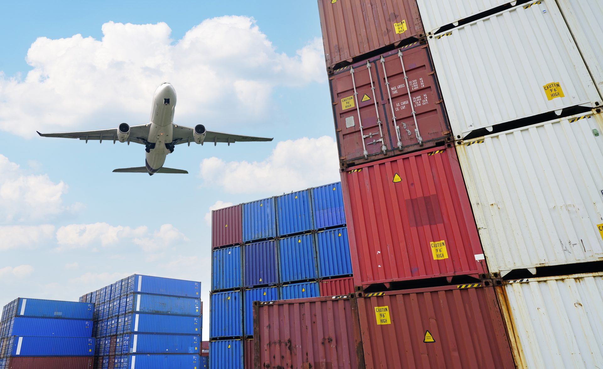 Aircraft flying over stacked shipping containers